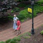 Two alums walk on the sidewalk on campus